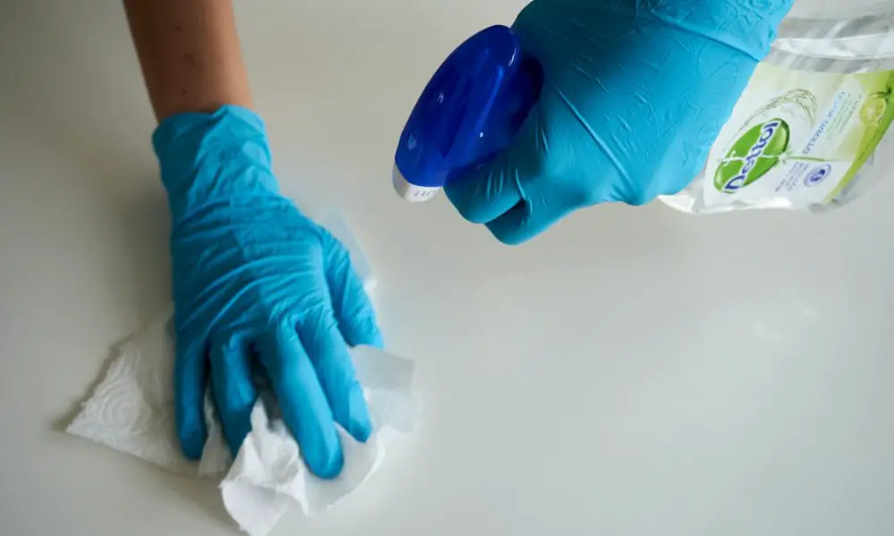 person in blue gloves holding white textile