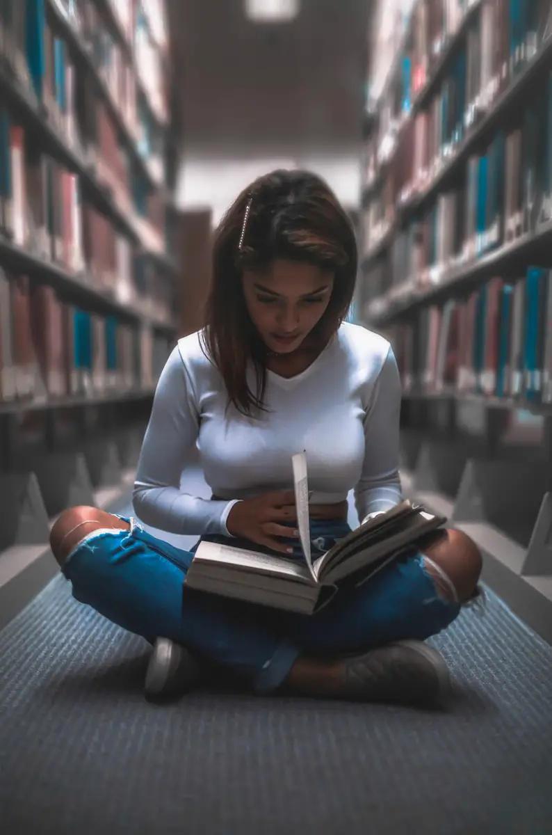 woman sitting between bookshelf