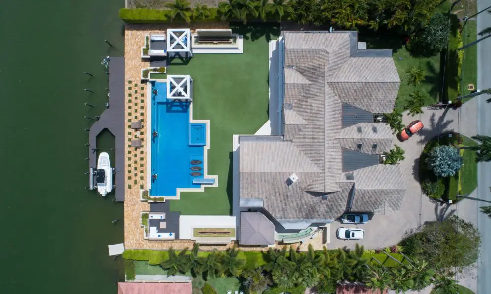 bird's eye view of house with pool near body of water