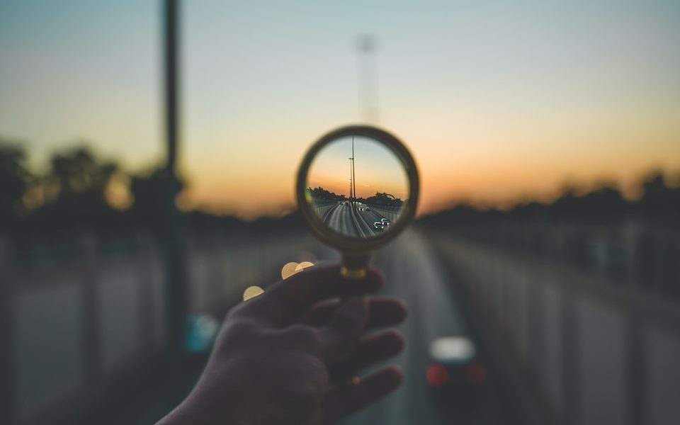 person holding magnifying glass during sunset