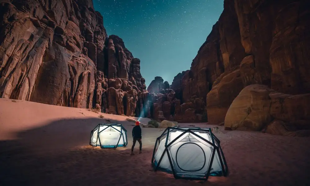 a man standing next to a tent in the desert