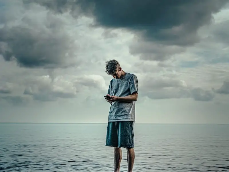 woman in white long sleeve shirt and blue skirt standing on rock in front of sea