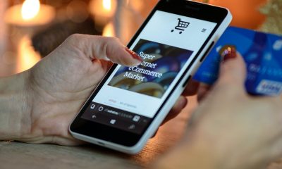 Person Using Black And White Smartphone and Holding Blue Card