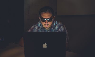 man wearing sunglasses using MacBook