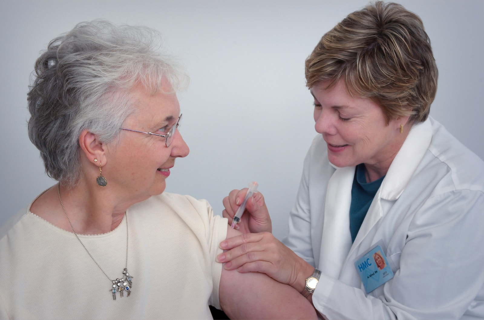 woman inject a woman on left shoulder