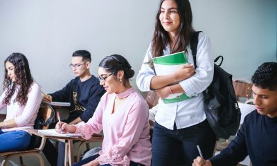 woman carrying white and green textbook