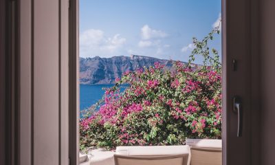 opened window showing outdoor lounger and pink flowers with mountain background