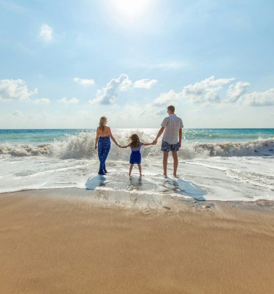 man, woman and child holding hands on seashore